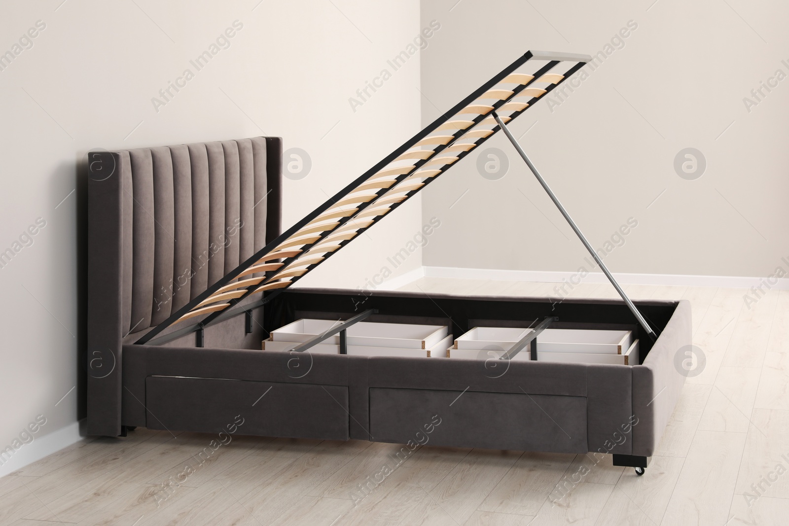 Photo of Comfortable bed with storage space for bedding under lifted slatted base in room