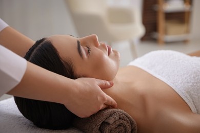 Young woman enjoying professional massage in spa salon, closeup