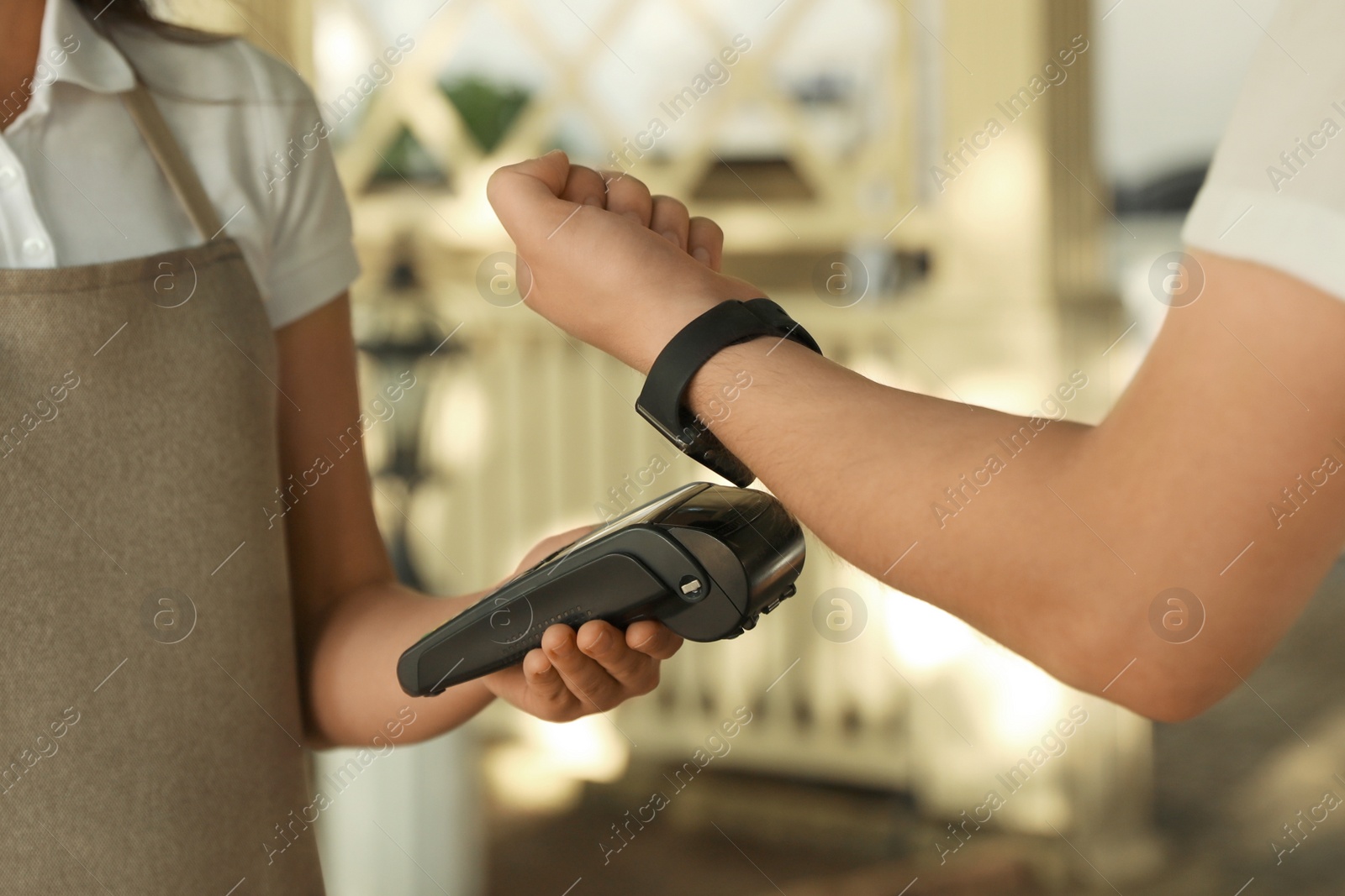 Photo of Man using terminal for contactless payment with smart watch in cafe, closeup