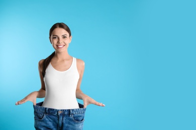 Photo of Attractive young woman with slim body wearing her old big jeans on color background. Space for text