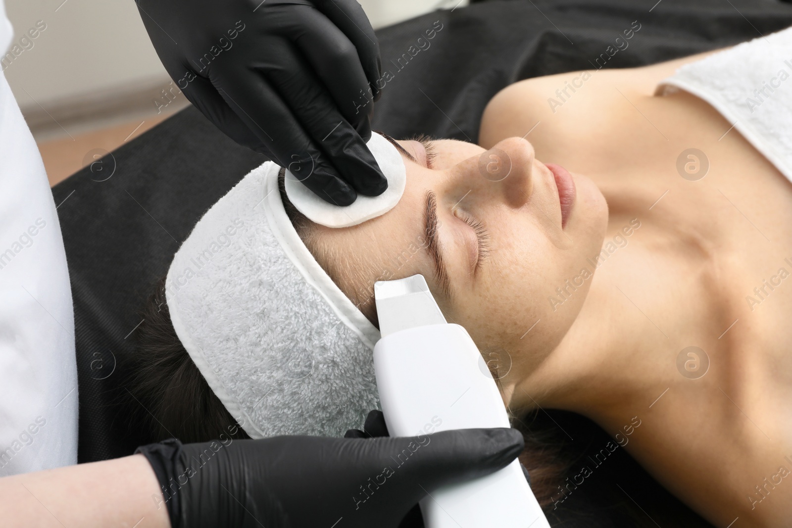 Photo of Cosmetologist using ultrasonic scrubber, closeup. Client having cleansing procedure indoors