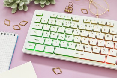 Photo of Modern RGB keyboard on pink background, above view