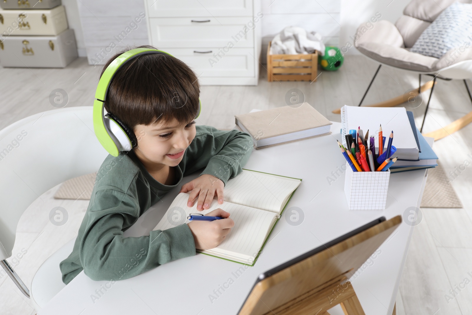 Photo of Cute little boy with modern tablet studying online at home. E-learning