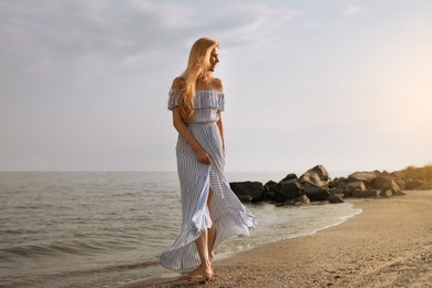 Beautiful young woman near water on sea beach