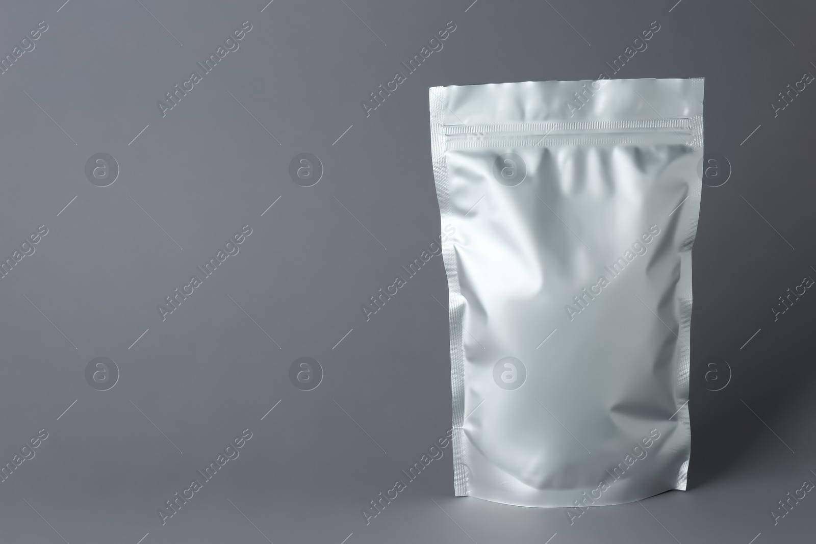 Photo of One blank foil package on grey background. Space for text