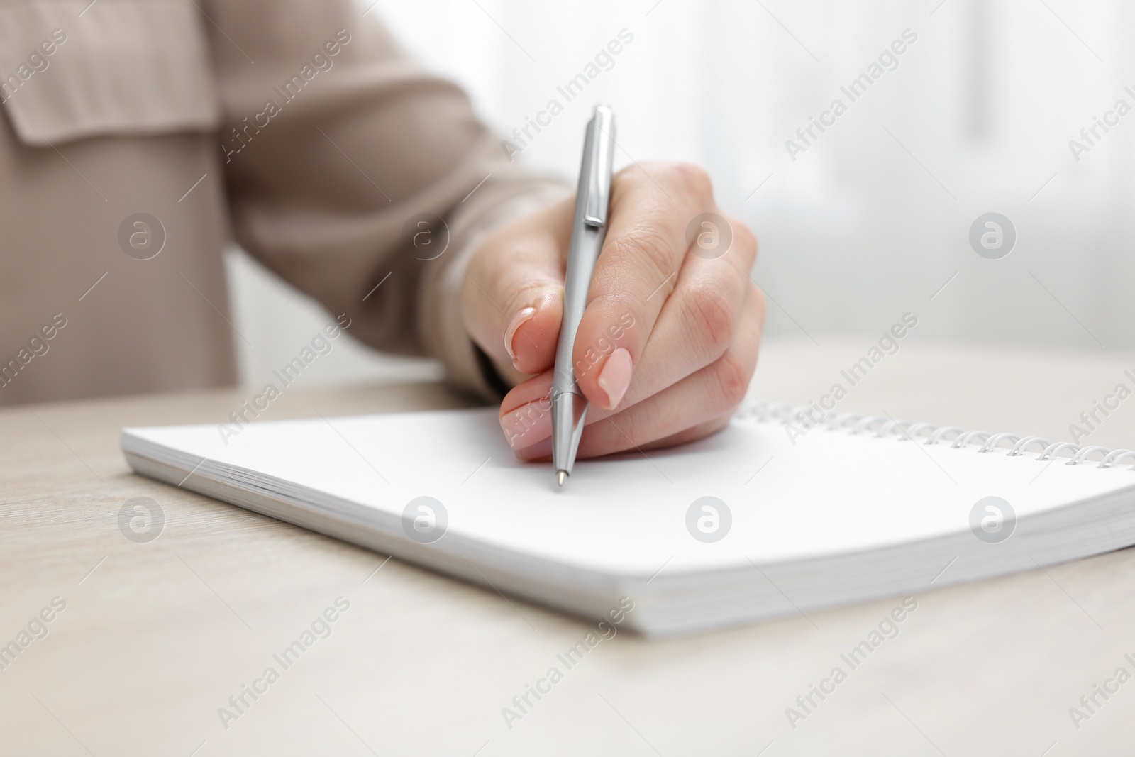 Photo of Woman writing in notebook at light table, closeup