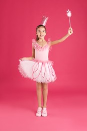 Photo of Cute girl in fairy dress with crown and magic wand on pink background. Little princess