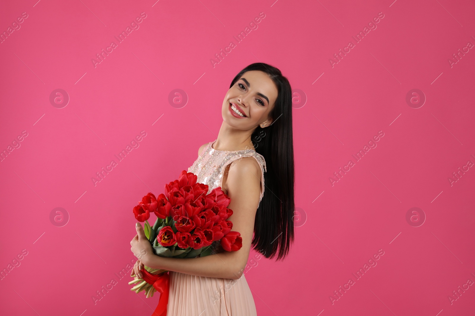 Photo of Happy woman with red tulip bouquet on pink background. 8th of March celebration