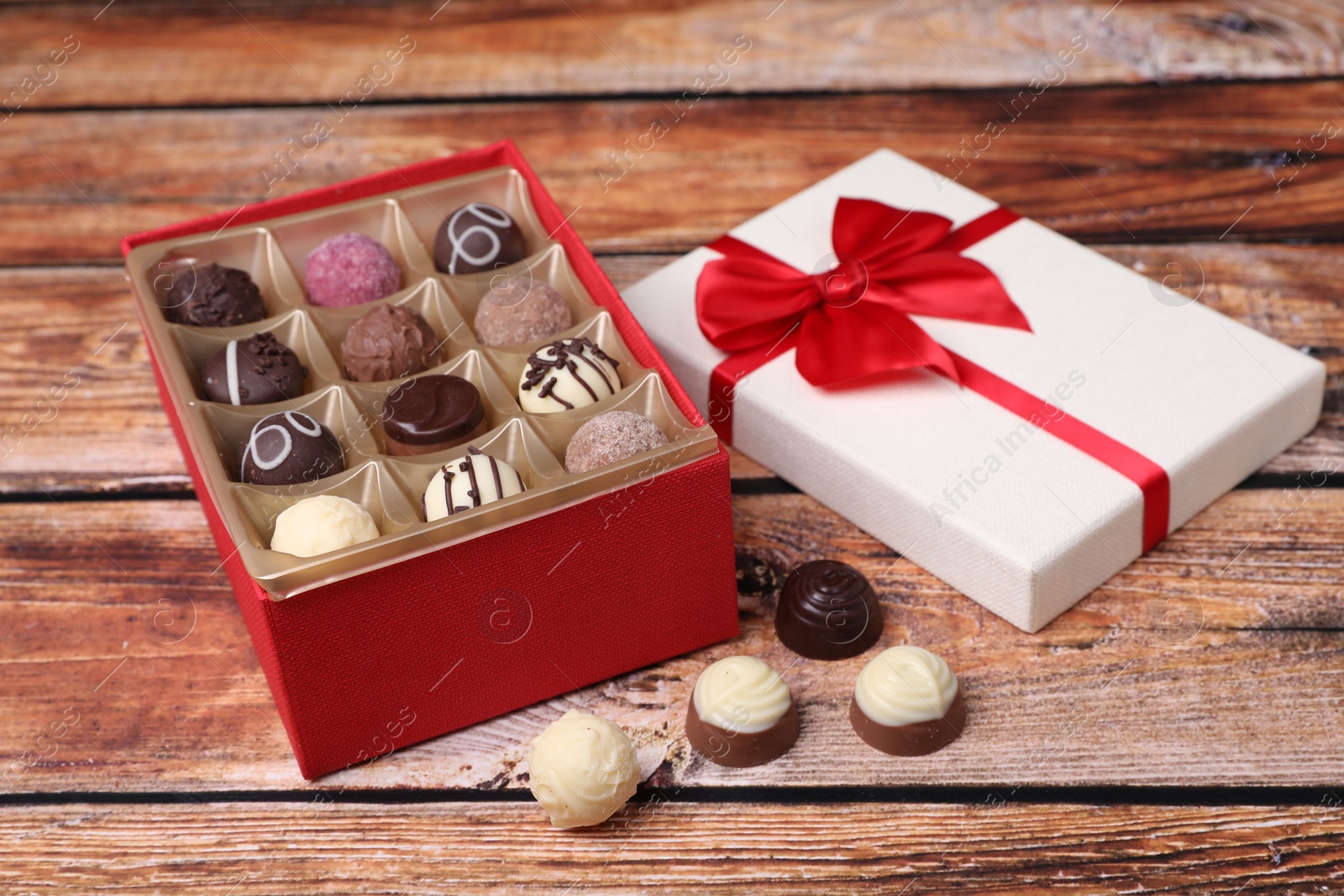 Photo of Red box with tasty chocolate candies on wooden table