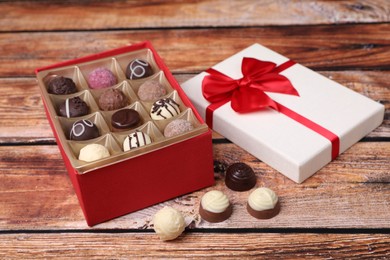 Red box with tasty chocolate candies on wooden table