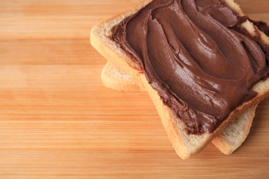 Photo of Tasty toast with chocolate paste on wooden table, above view. Space for text