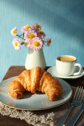 Delicious fresh croissant served with coffee on table