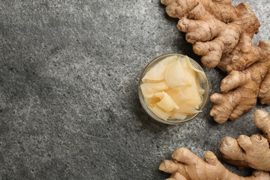 Spicy pickled ginger and root on grey table, flat lay. Space for text