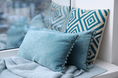 Photo of Soft pillows and blanket on window sill indoors