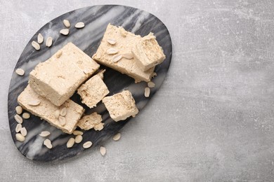 Pieces of tasty halva on light gray table, top view. Space for text