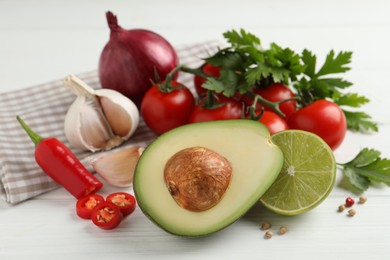 Fresh ingredients for guacamole on white wooden table