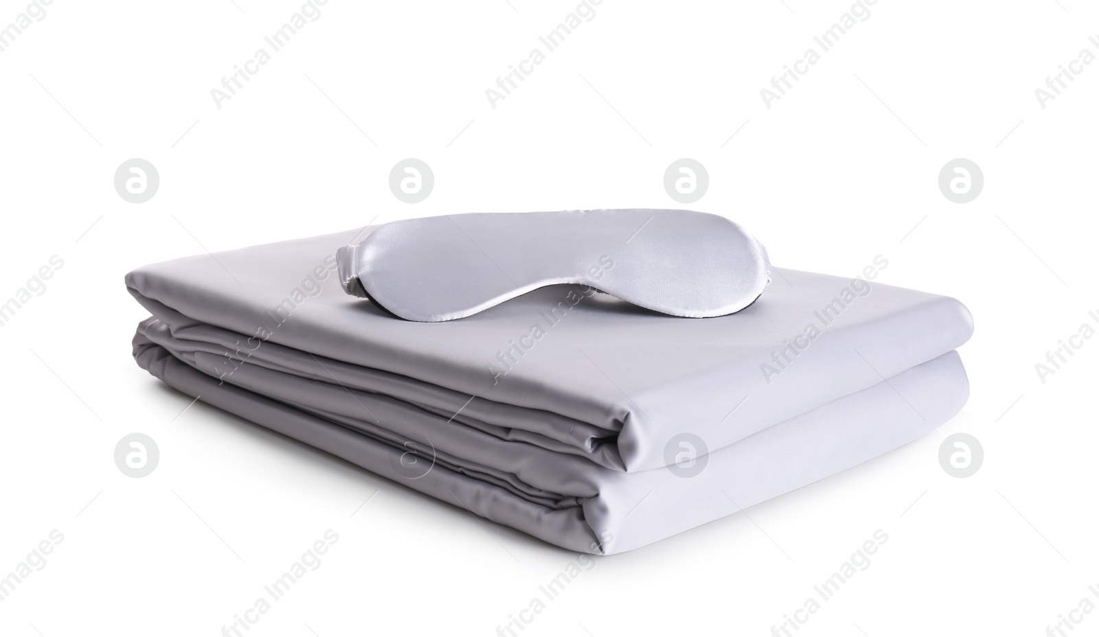 Photo of Stack of clean silky bed linen and sleeping mask isolated on white