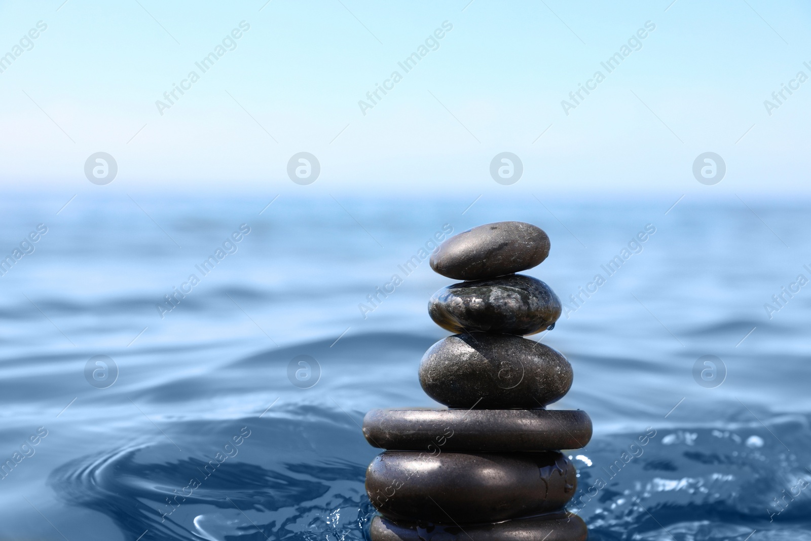 Photo of Stack of stones in sea water, space for text. Zen concept