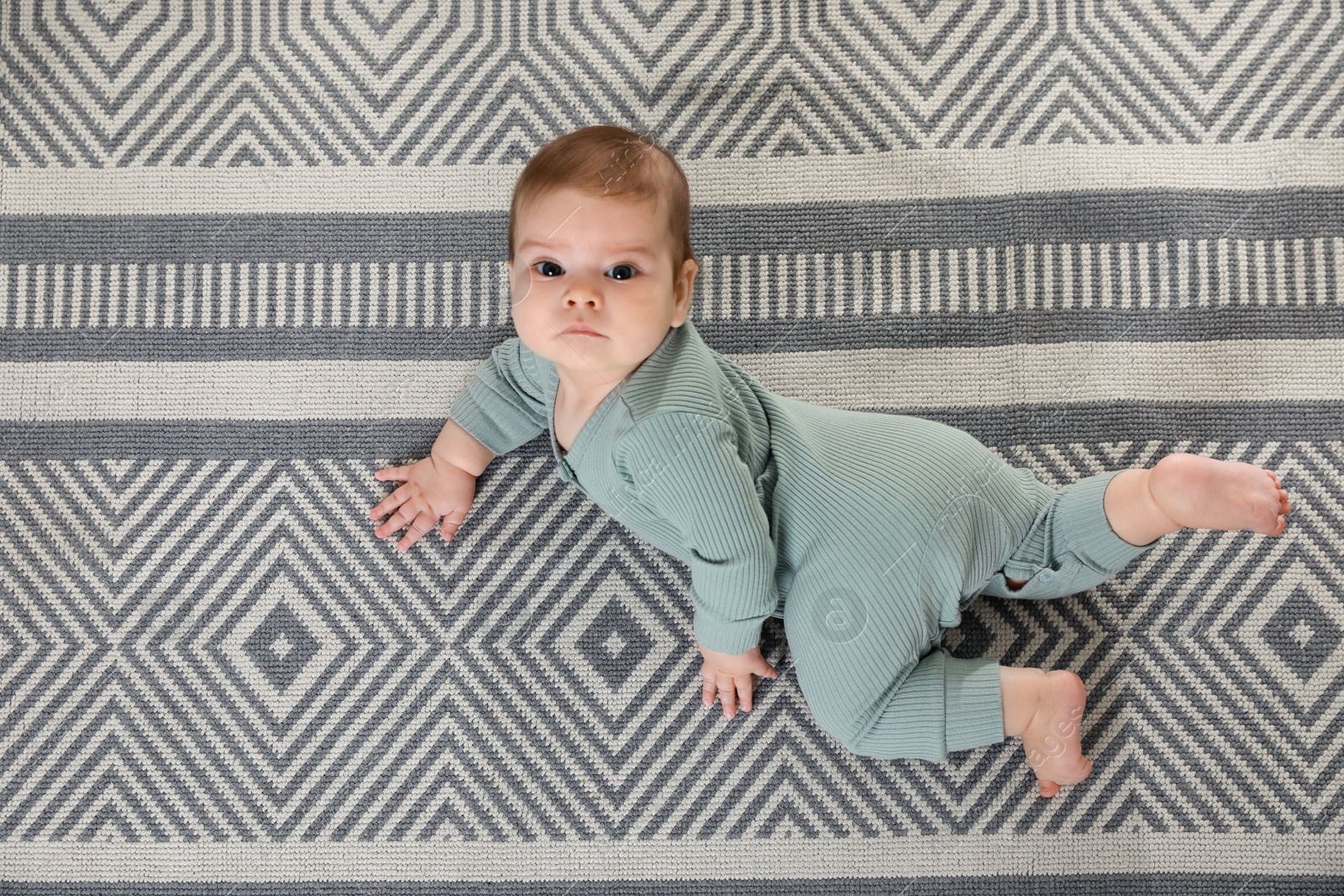 Photo of Cute baby crawling on floor, top view