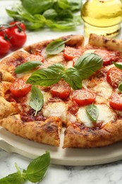 Photo of Delicious Margherita pizza and ingredients on white marble table, closeup