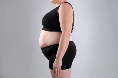 Photo of Fat woman on grey background, closeup. Weight loss