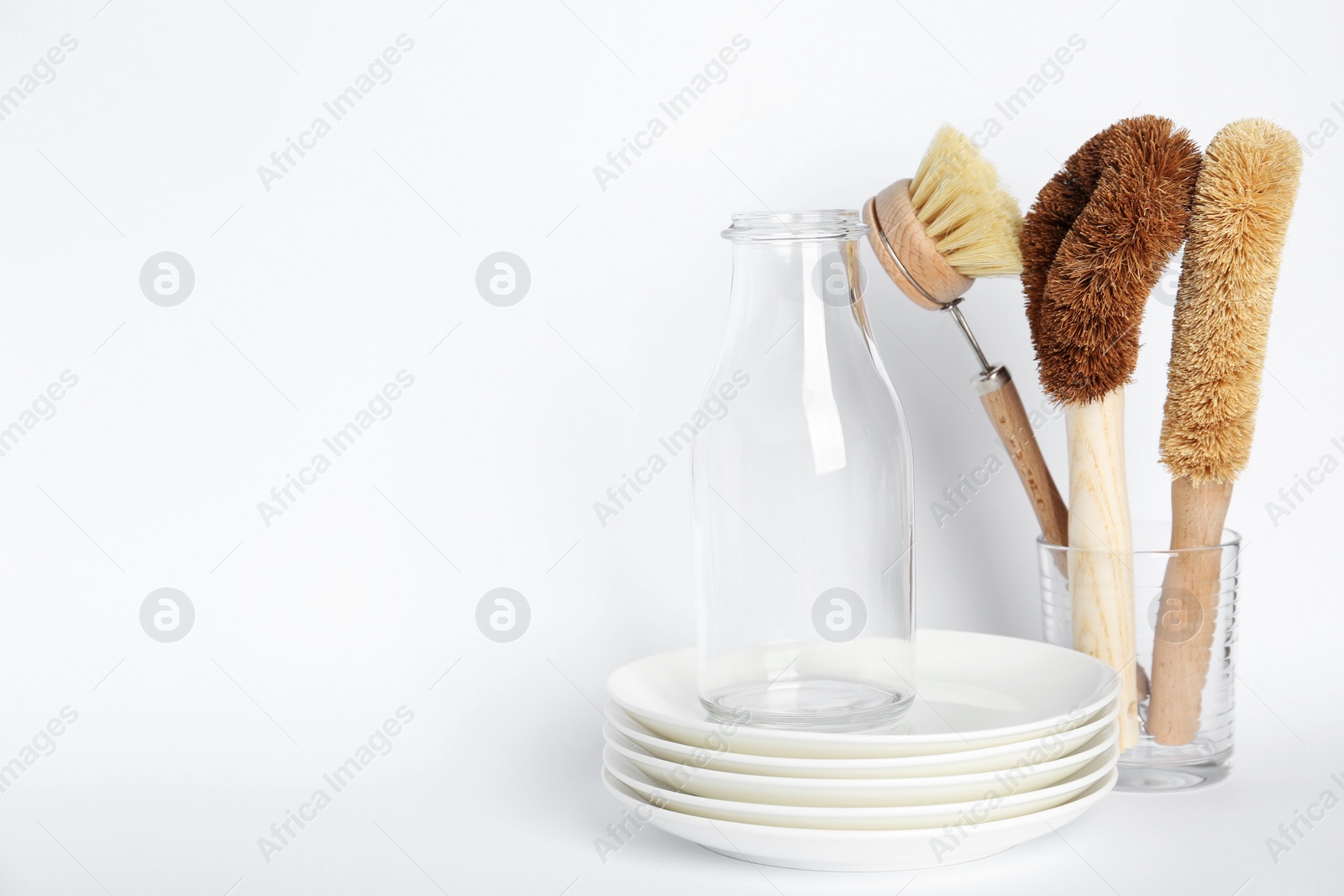 Photo of Cleaning brushes for dish washing, bottle and plates on white background