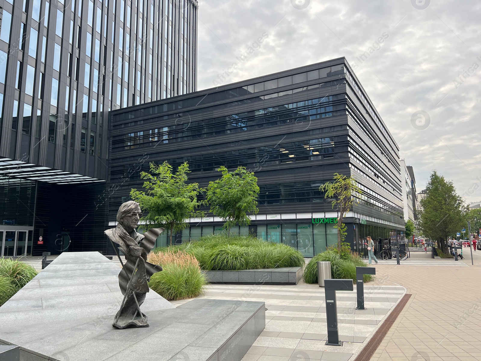 Photo of WARSAW, POLAND - JULY 13, 2022: Beautiful view of city street with big building, sculpture and green trees