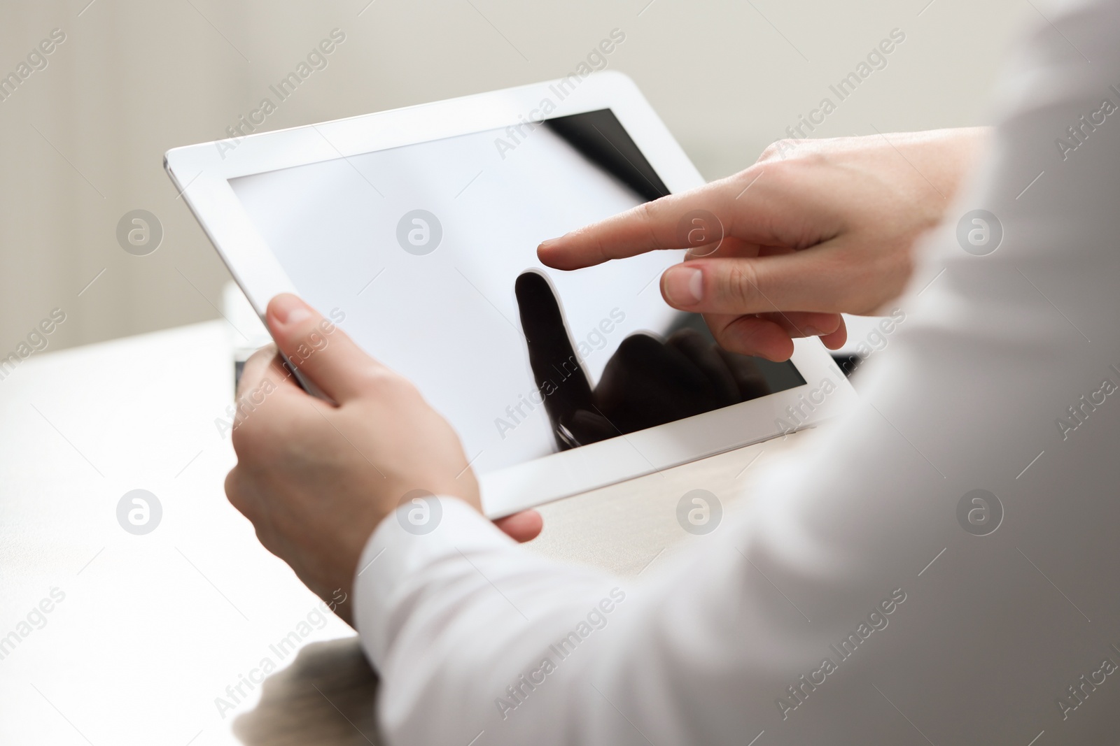 Photo of Man using tablet at wooden table, closeup