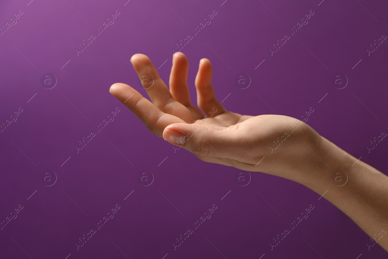 Photo of Woman holding something in hand on purple background, closeup