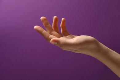 Woman holding something in hand on purple background, closeup