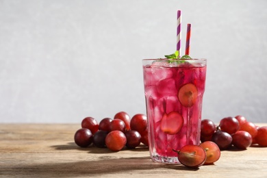 Photo of Delicious grape soda water with mint and berries on wooden table. Refreshing drink