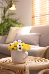Photo of Cup with beautiful bright flowers on table in living room