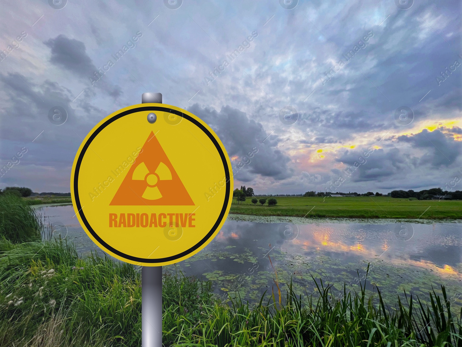 Image of Radioactive pollution. Yellow warning sign with hazard symbol near lake