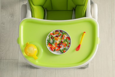 Photo of Baby high chair with healthy food and water, top view