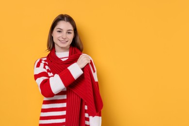 Photo of Beautiful woman in warm scarf on yellow background, space for text