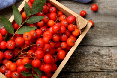 Photo of Fresh ripe rowan berries with green leaves on wooden table, flat lay