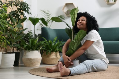 Photo of Relaxing atmosphere. Happy woman hugging ficus near another potted houseplants in room