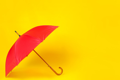 Beautiful red umbrella on light yellow background. Space for text