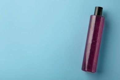 Photo of Bottle of pink cosmetic gel on light blue background, top view. Space for text