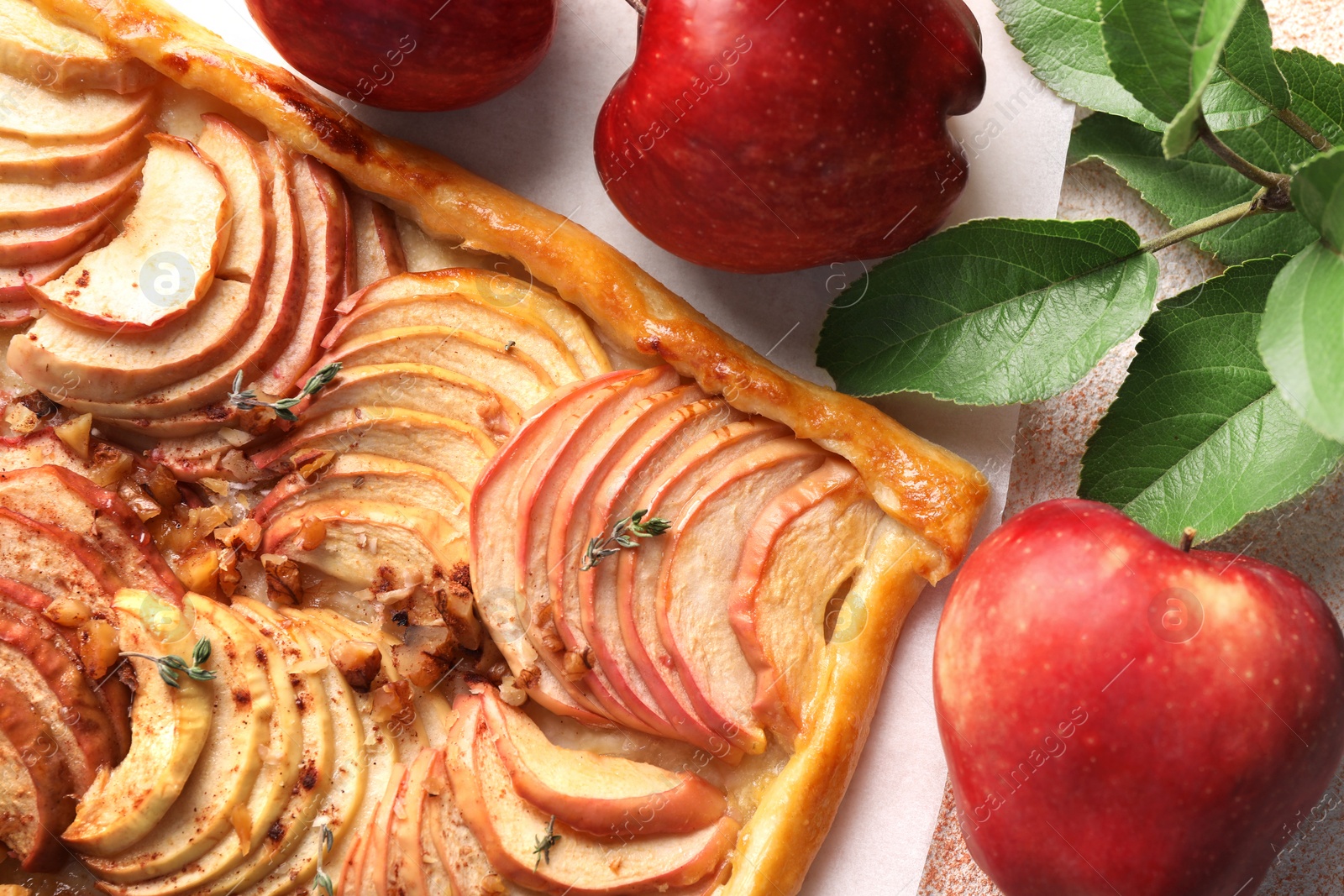 Photo of Tasty apple pie with nuts, fresh fruits and leaves on table, flat lay