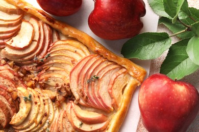 Tasty apple pie with nuts, fresh fruits and leaves on table, flat lay