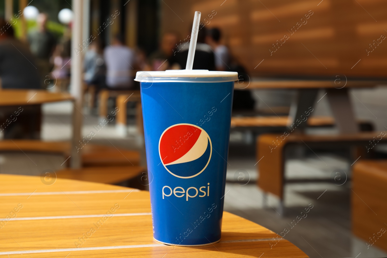 Photo of MYKOLAIV, UKRAINE - JUNE 9, 2021: Paper Pepsi cup on wooden table outdoors