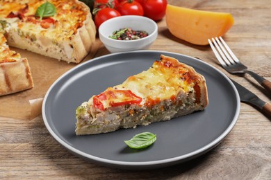 Tasty quiche with tomatoes, basil and cheese served on wooden table, closeup