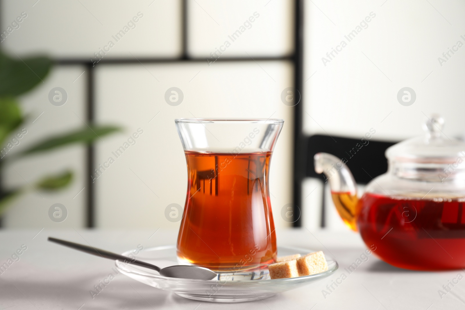 Photo of Traditional Turkish tea in glass and sugar cubes on white table