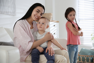 Photo of Unhappy little girl feeling jealous while mother spending time with her baby brother at home