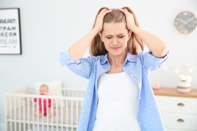 Photo of Young mother suffering from postnatal depression and little baby in room