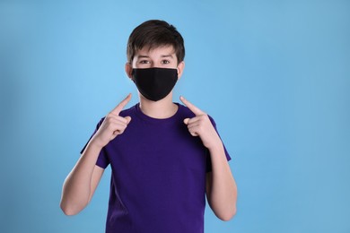 Boy wearing protective mask on light blue background. Child safety