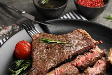 Photo of Delicious grilled beef steak with spices and tomato served on table, closeup