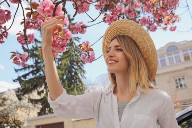 Happy female tourist near blossoming sakura outdoors on spring day