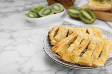 Photo of Fresh tasty puff pastry with kiwi on white marble table. Space for text